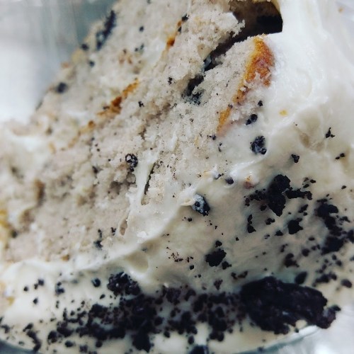 Close-up of a slice of cake with creamy frosting and chocolate crumbs on top.