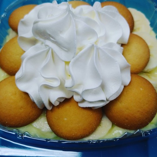 A dessert featuring a creamy layer topped with whipped cream and vanilla wafers.
