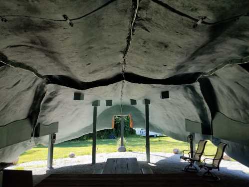 Interior view of a unique, curved structure with green walls and a grassy area visible outside.