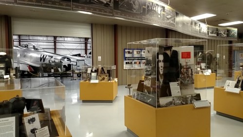 Interior of a museum featuring aircraft displays and various historical exhibits in glass cases.