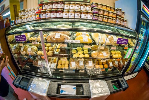 A display case filled with various baked goods, including bread and pastries, with jars of preserves on top.