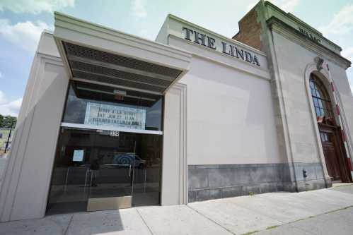 Entrance of The Linda, a venue with a marquee displaying an event, set against a clear blue sky.