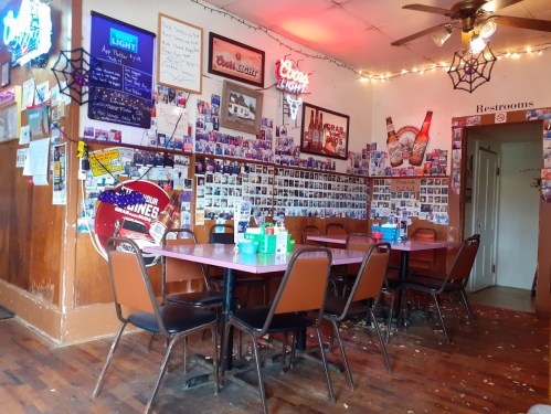 A cozy diner with colorful decor, tables set for dining, and walls adorned with photos and neon signs.