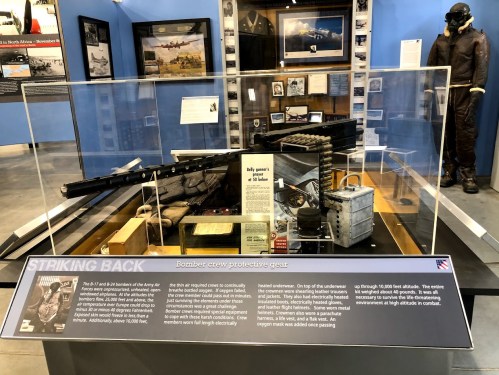 Exhibit display featuring bomber crew protective gear and historical artifacts, titled "Striking Back."
