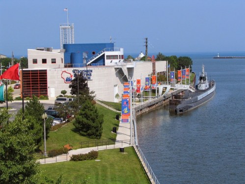 A view of the Wisconsin Maritime Museum with a docked submarine and colorful banners along the waterfront.