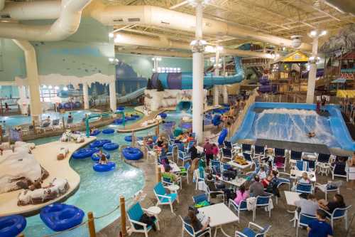 Indoor water park featuring slides, a wave pool, lazy river, and families enjoying the attractions and dining areas.