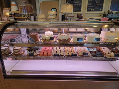 A display case filled with various cakes and pastries, showcasing colorful desserts and layered cakes.