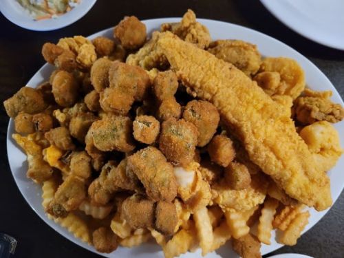 A large platter filled with various fried foods, including fish, hushpuppies, and crinkle-cut fries.