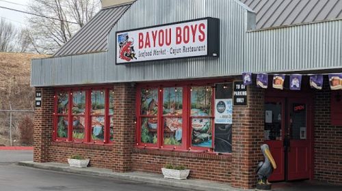 Exterior of Bayou Boys restaurant, featuring a sign and colorful window displays, with a parking area in front.