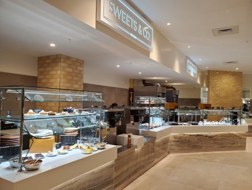 A modern dessert shop display featuring various pastries and sweets in a well-lit, elegant setting.