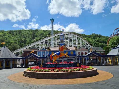 Colorful entrance to Lake Compounce amusement park, featuring a horse statue and a roller coaster in the background.