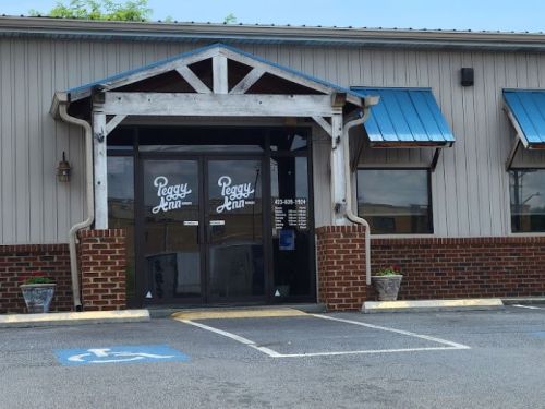 Entrance of a building with a sign reading "Peggy Ann," featuring blue awnings and brick accents.