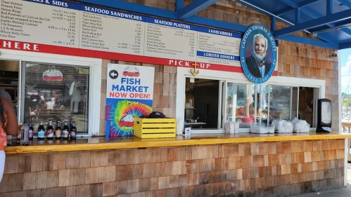 A seafood restaurant counter with a menu, colorful signage, and drinks displayed. Bright and inviting atmosphere.