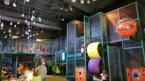 A colorful indoor play area with climbing structures, slides, and children playing in a vibrant, enclosed space.