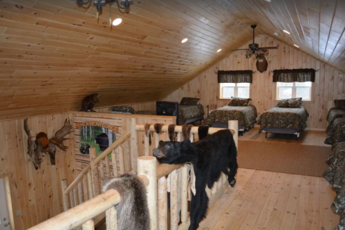 Cozy wooden loft with beds, rustic decor, and animal mounts, featuring a warm, inviting atmosphere.