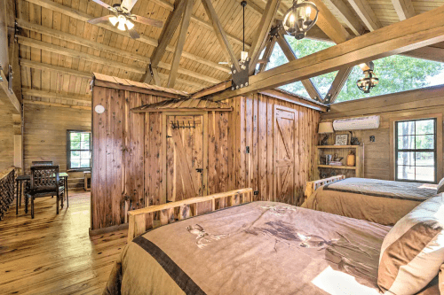 Cozy wooden bedroom with two beds, rustic decor, and large windows letting in natural light.