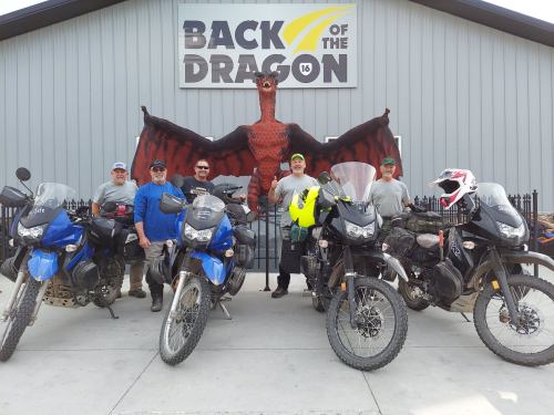 A group of five motorcyclists poses with their bikes in front of a dragon-themed sign at Back of the Dragon.