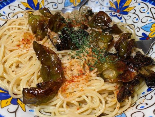 A colorful plate of spaghetti topped with roasted vegetables and herbs, served in a decorative bowl.