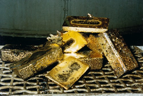 A pile of gold bars resting on a metal grate, showcasing their shiny surfaces and intricate details.