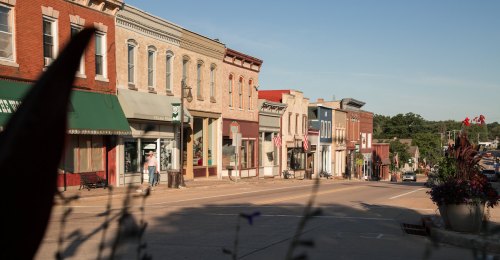 A charming small-town street lined with historic buildings and shops under a clear blue sky.