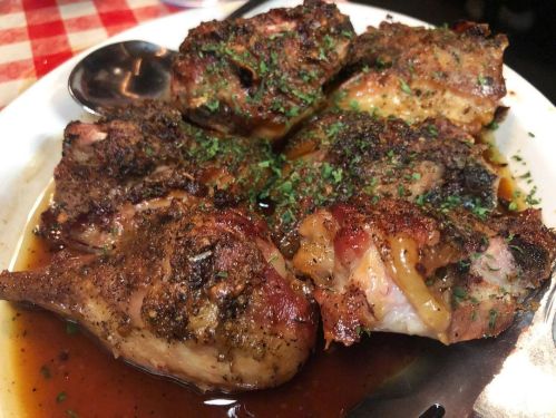 A plate of seasoned, grilled meat pieces garnished with herbs, served in a savory sauce.