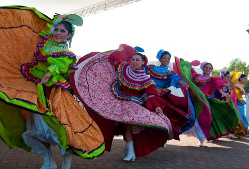 A group of dancers in colorful traditional costumes performing a lively dance outdoors.