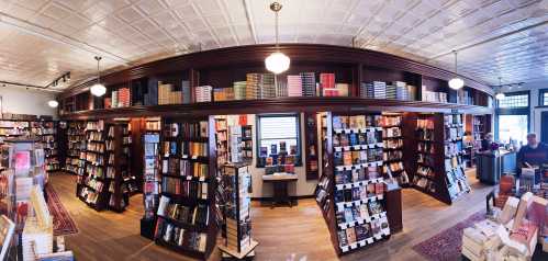 A cozy bookstore interior with wooden shelves filled with books, warm lighting, and a welcoming atmosphere.