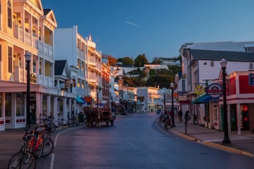 A quiet street lined with colorful buildings, bicycles, and a horse-drawn carriage, bathed in warm morning light.