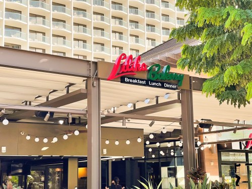 Sign for "Litko Bakery" with options for breakfast, lunch, and dinner, set against a modern building backdrop.