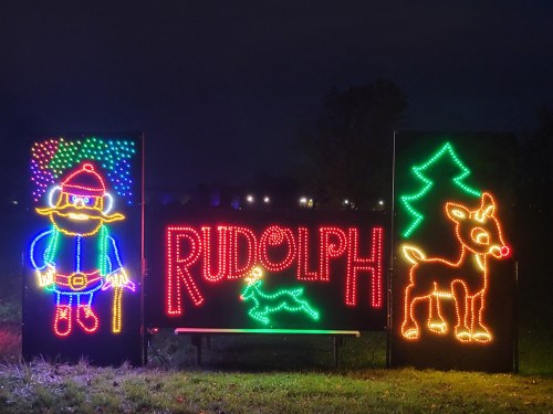 Colorful holiday lights display featuring Rudolph the red-nosed reindeer, a tree, and a whimsical character.