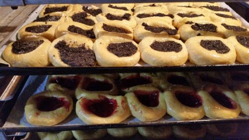 Trays of freshly baked pastries filled with poppy seed and fruit jam, arranged in a bakery oven.