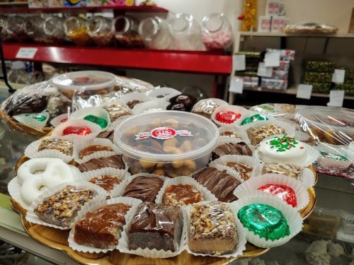 A variety of colorful, wrapped sweets and desserts displayed on a platter in a candy shop.