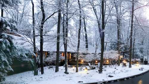 A cozy cabin surrounded by snow-covered trees, illuminated softly in a winter landscape.