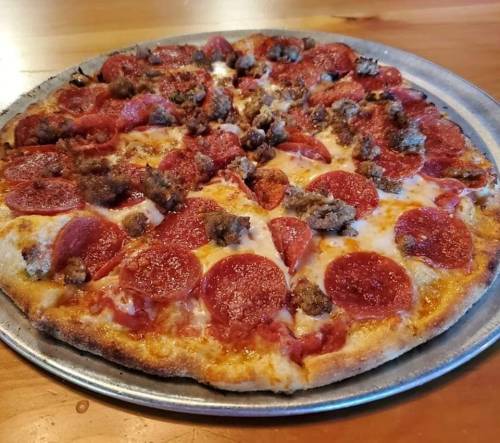 A freshly baked pizza topped with pepperoni and sausage on a metal tray.