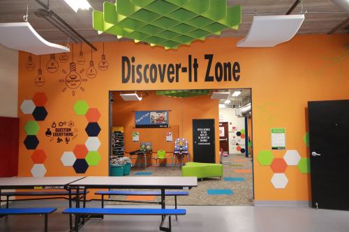 Brightly colored room labeled "Discover-It Zone" with hexagonal patterns and a welcoming entrance.