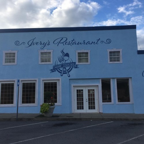 A blue building with the sign "Ivery's Restaurant" and "Home Cooking" on the front, featuring large windows.