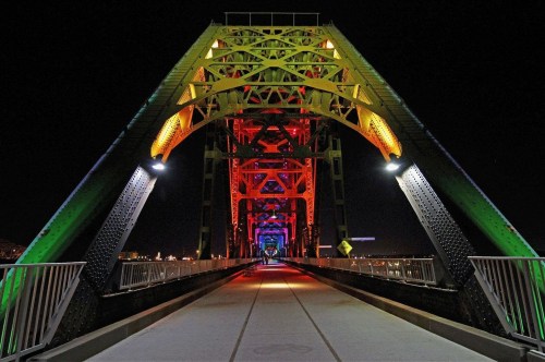 A brightly lit bridge at night, showcasing colorful arches and a clear pathway beneath.