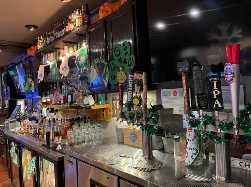A bar with a variety of liquor bottles, taps, and St. Patrick's Day decorations, including shamrocks and green accents.