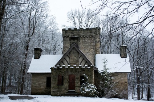 A stone castle-like structure surrounded by snow-covered trees in a winter landscape.