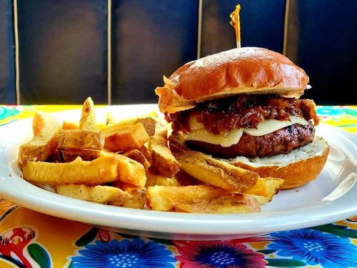 A juicy burger with melted cheese and crispy bacon, served with golden fries on a colorful table.
