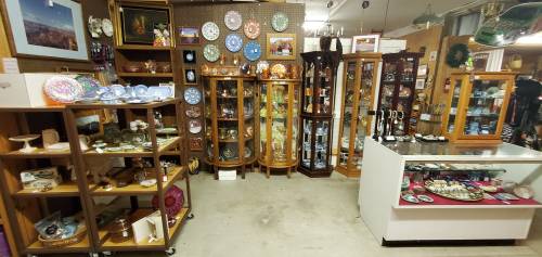 A vintage shop interior featuring display cases with various collectibles, plates, and decorative items.