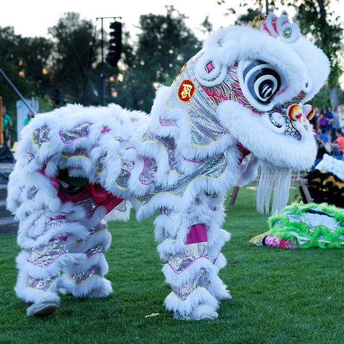 A colorful lion dance costume with intricate details, set on green grass during a cultural festival.