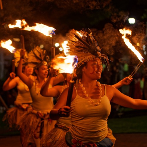 A group of performers in traditional attire dance with torches, showcasing vibrant cultural expressions at night.