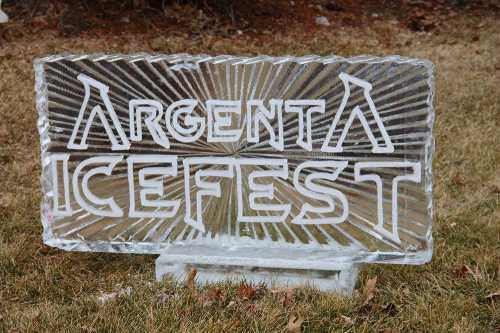 Clear ice sculpture sign reading "Argenta IceFest" on grass.