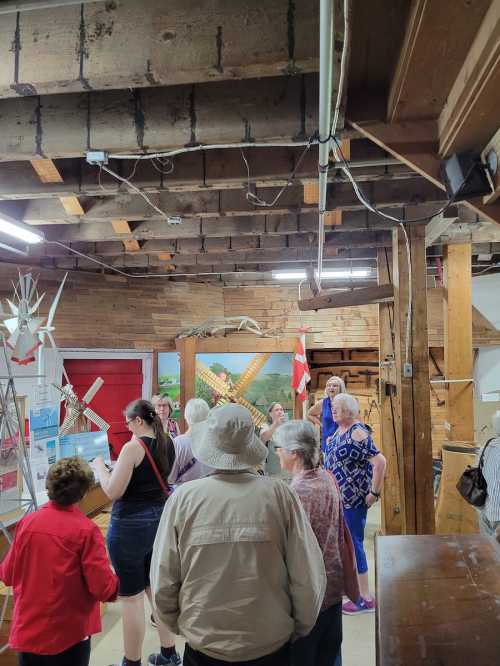 A group of people exploring a rustic museum with wooden beams and various exhibits in the background.