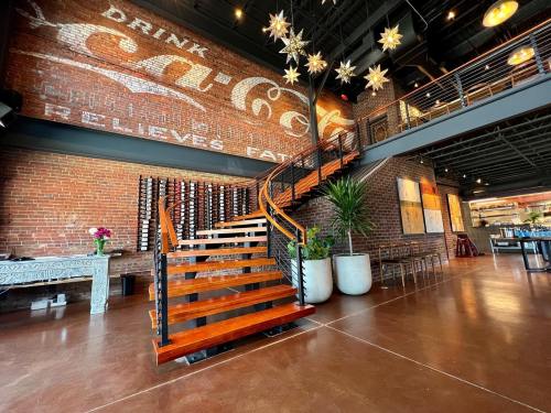 A modern interior featuring a wooden staircase, exposed brick wall with a vintage Coca-Cola sign, and stylish decor.