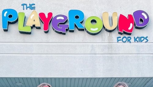 Colorful sign reading "The Playground for Kids" above two smiling children.