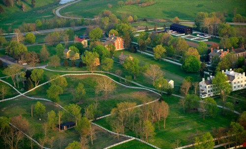Aerial view of a lush green landscape featuring historic buildings and winding paths surrounded by trees.