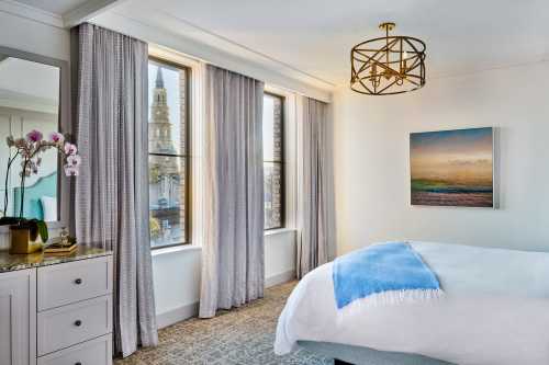 Bright, modern bedroom with a large window showcasing a tower view, featuring soft curtains and a cozy bed.