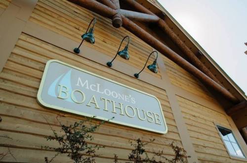 Sign for McLoone's Boathouse on a wooden building, featuring outdoor lighting fixtures.